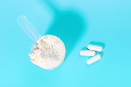 Scoop with protein powder and capsules on blue background top view.の写真素材