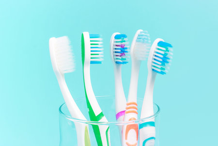 Toothbrushes in glass cup on blue background close-up.