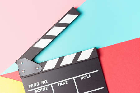 The clapperboard on pink, blue and red background close-up, top view.の写真素材