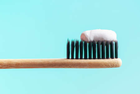 Bamboo toothbrush with toothpaste on blue background close-up.の写真素材