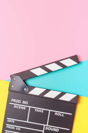 The clapper board on pink, yellow and blue background close-up.の写真素材