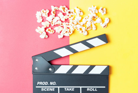 The clapperboard and popcorn on yellow and red background top view.