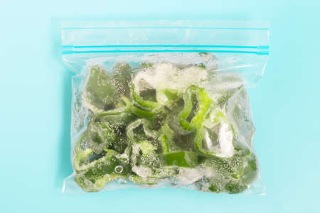 Frozen green peppers in a transparent bag close-up on blue background.の写真素材