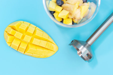 Hand blender and bowl with fruit on blue background top view.の写真素材