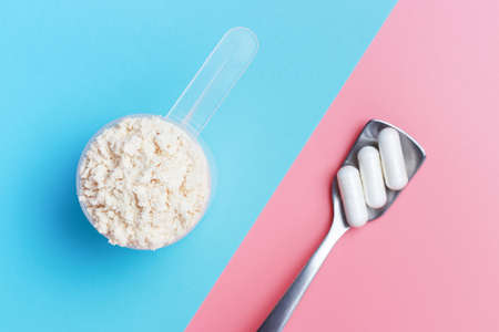 Protein scoop and capsules on pink and blue background close-up, top view.の写真素材