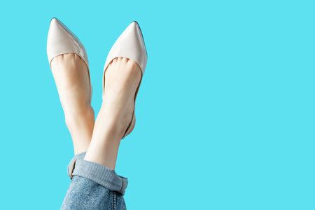 Female legs in summer brown shoes on blue background, copy space.
