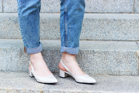 Female legs in jeans and beige shoes on the background of concrete staircase.の写真素材