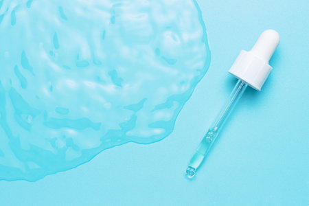 Pipette with serum on blue background close-up, concept of natural cosmetics.