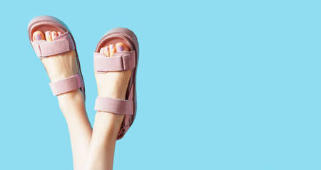 Female legs in pink sandals upside down on blue background, copy space.の写真素材