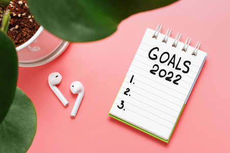The inscription goals 2022 on notepad and headphones on pink background.の写真素材
