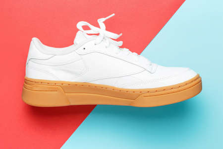 White sneaker with brown sole on red and blue background close-up.の写真素材