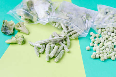 Frozen vegetables in plastic bags on green background, top view.の写真素材
