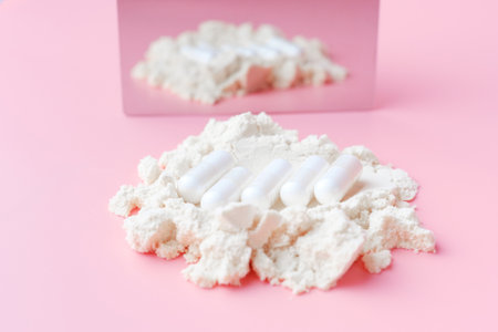 Reflection in the mirror of wooden spoon with collagen on pink background.の写真素材