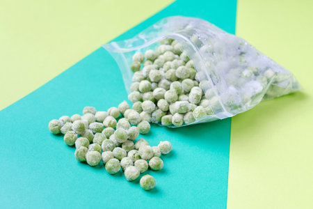 Scattered peas in plastic bag on a green background close-up.の写真素材