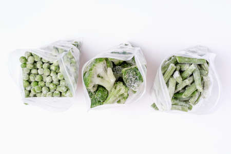 Open packages with frozen vegetables inside on white background top view.の写真素材