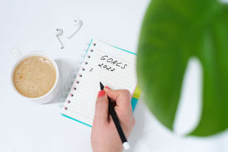 Female hand writes goals 2022 in notebook on white background top view.の写真素材