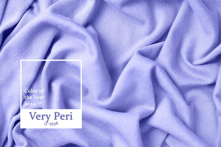 Inscription color of the year 2022 on the folds of knitted clothes close-up.