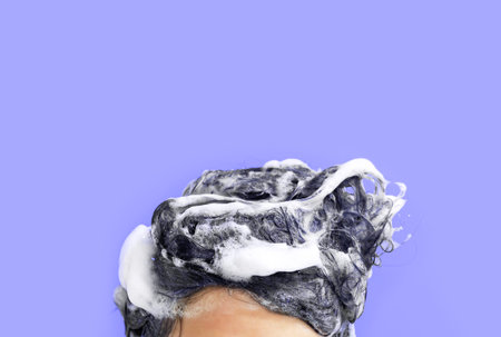 Female head with hair in foam close-up on purple background.