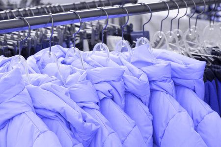 Down jackets on hanger in store close-up, trending color concept of the year 2022.の写真素材