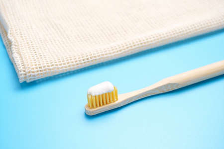 Bamboo toothbrush on a blue background close-up, side view.の写真素材