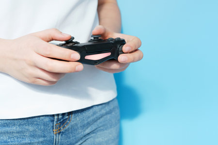 Female hands holding video game joystick on blue background, front view.の写真素材