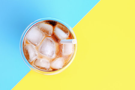 Ice coffee in glass glass cup tube on yellow and blue background, top view.の写真素材