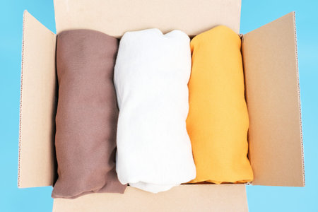 Stack of clothes in cardboard box top view, moving concept.