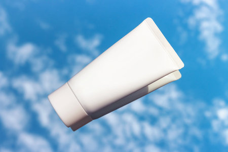 White tube with cream on the background of the sky with clouds close-up.