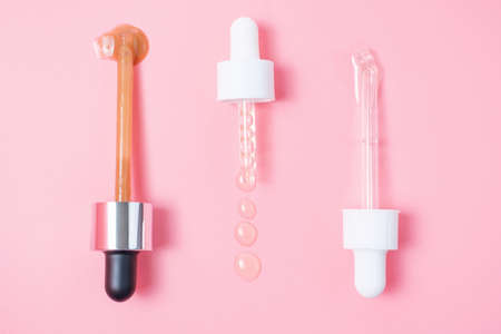 Three pipettes with serum and collagen on a pink background close up.の写真素材