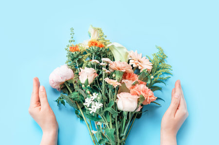 Beautiful bouquet and female hands on a blue background top view.の写真素材