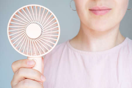 Woman holding pink mini fan close up front view.の写真素材