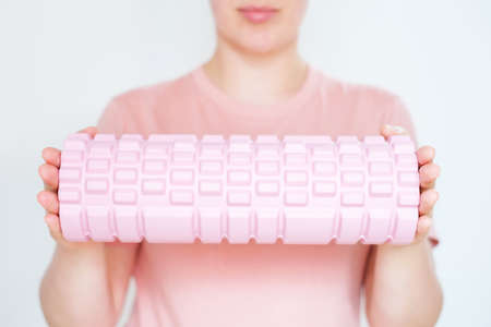 Young woman hold a massage foam roller on white background close-up, selective focus.の写真素材