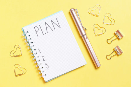 Inscription Plan in a blank notepad and stationery on a yellow background copy space.