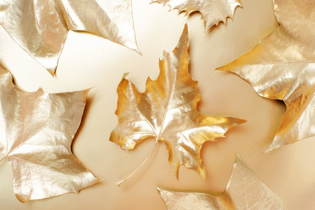 Pattern of golden maple leaves on a golden background close-up, top view.の写真素材