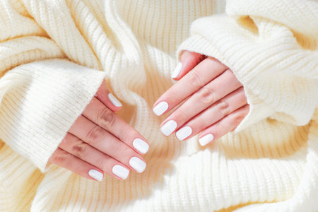 Female hands with white manicure isolated on knitted background.の写真素材