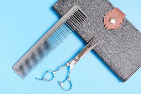 Professional scissors and a comb for hairdresser on blue background close-up, top view.の写真素材
