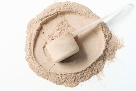 Scattered protein and measuring spoon on white background top view, concert of sports nutrition.の写真素材