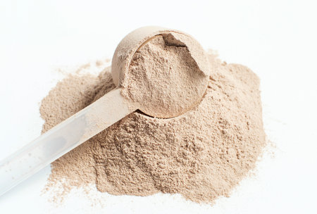 Scattered protein and measuring spoon on white background side view, concert of sports nutrition.の写真素材