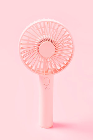 Portable mini fan on pink background close-up, front view.の写真素材