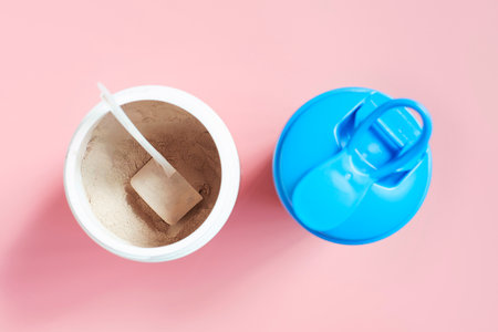 Plastic jar with brown protein and cocktail shaker on pink background top view.の写真素材