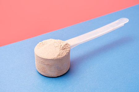 Chocolate protein powder in scoop on pink and blue background.の写真素材