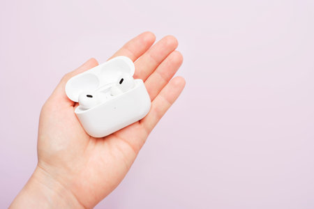 Seoul - 05.02.2023: female hand holds Apple AirPods Pro 2nd generation on pink background.のeditorial素材