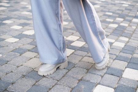 Female legs in gray shoes on wide platform in the street close-up.の写真素材