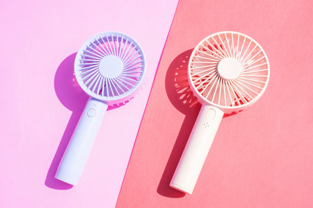 Small portable mini fans on pink background close-up.の写真素材