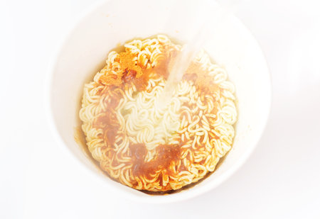 Water is poured into a box with instant noodles on a white background top view.の写真素材