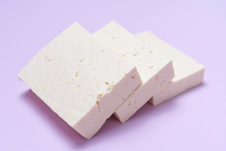 A sliced pieces of tofu on lilac background close-up, side view.の写真素材