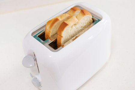 Pieces of bread in a toaster on white background, side view.の写真素材