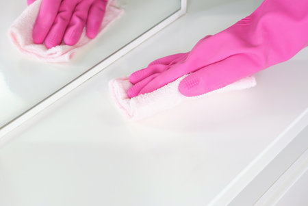 Female hand in a pink glove wipes surface with rag.の写真素材