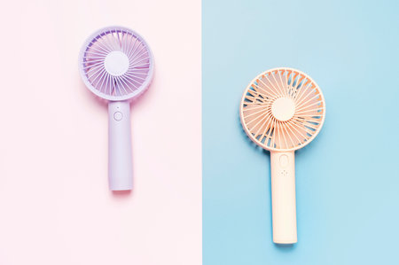 Small portable mini fans on blue and pink background close up.の写真素材