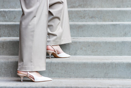 Side view of female legs in gray trousers and pointed sandals against the background of stairs.の写真素材